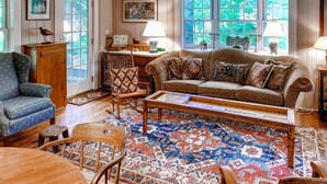 Un salon chaleureux avec un tapis à motifs, un canapé, un fauteuil et un meuble en bois.