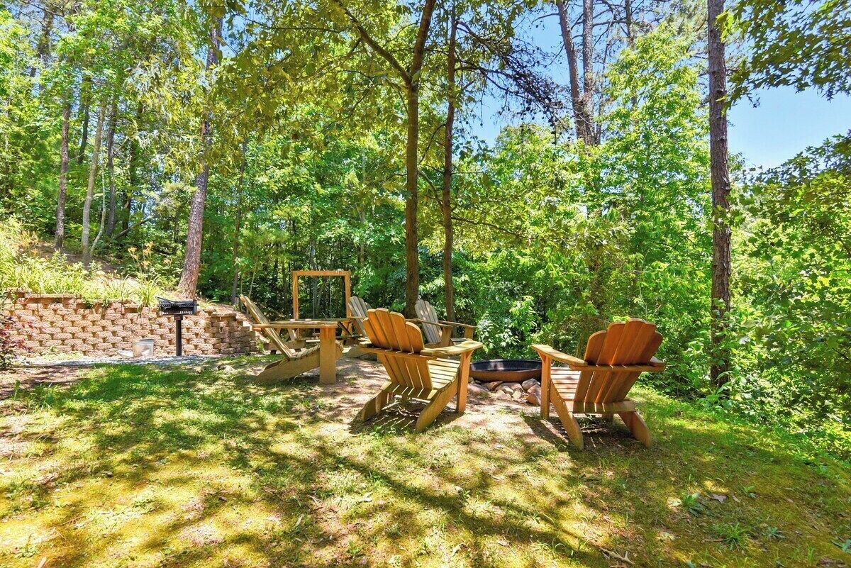 Un espacio al aire libre con sillas Adirondack y un pozo de fuego.