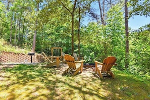An outdoor seating area with Adirondack chairs and a fire pit.