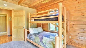 A bunk bed with a wooden frame and a colorful bedspread in a room with wooden walls and a sloped ceiling. - Close to hiking, waterfalls & fun! (Clyde)