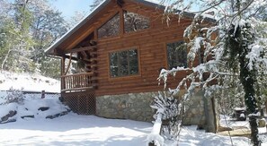 A wooden cabin with a stone foundation, a balcony, and snow-covered surroundings. - Close to hiking, waterfalls & fun! (Clyde)