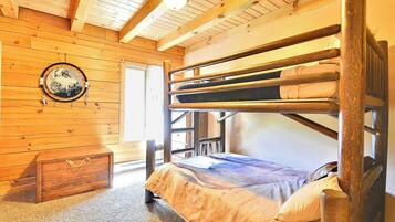 Una cama litera en una habitación de madera con un adorno circular en la pared y un pequeño aparador.