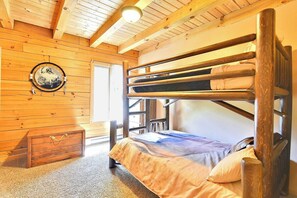 A bunk bed in a wooden room with a circular wall decoration and a small chest of drawers.