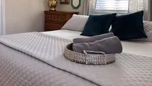 Una camera da letto con un letto, un comodino con una lampada, uno specchio e una finestra con tende.