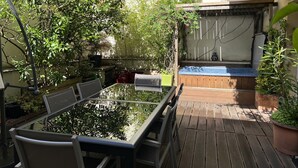 A glass-top dining table with chairs, a wooden deck, and a hot tub area.