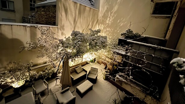 A courtyard with outdoor seating, a small table, and a decorative light.