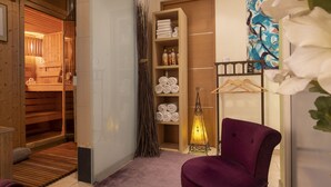 A room with a wooden sauna, shelves with towels, a hanging rack, and a purple chair.