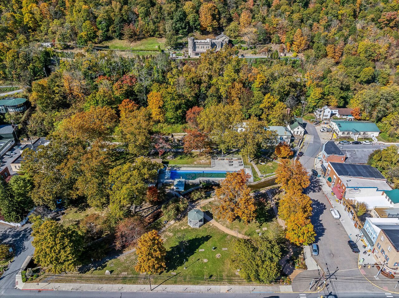 Vista aérea de una propiedad con piscina, un pabellón y un edificio grande rodeado de árboles.