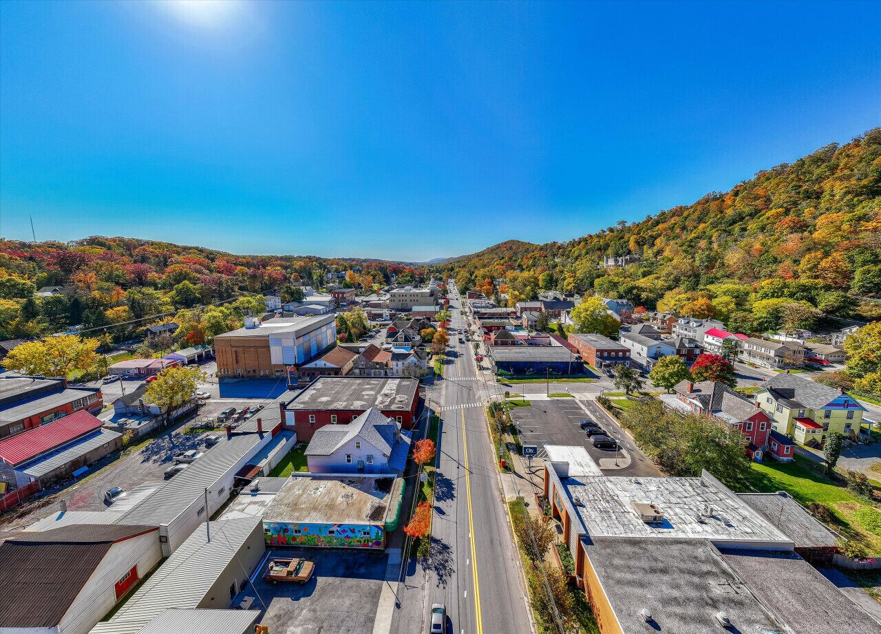 An aerial view of a town with buildings, roads, and a hilly landscape.