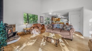 A cozy living room with a fireplace, a sofa, a coffee table, and a view of the kitchen.