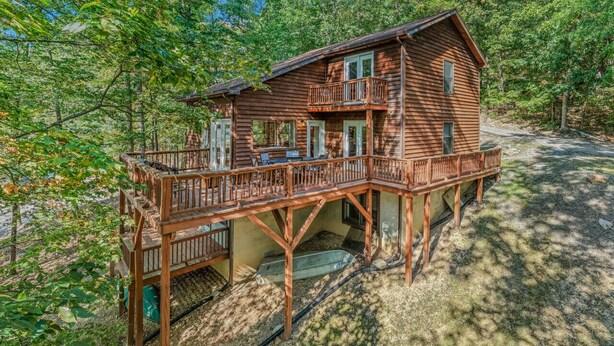 A wooden cabin with a deck, surrounded by trees.