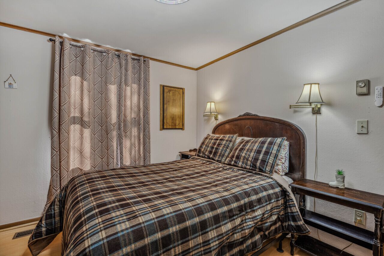 Une chambre à coucher avec un lit, des rideaux, des lampes de chevet, une table de chevet et un réveil fixé au mur.