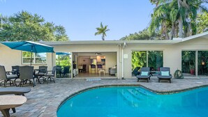 A backyard with a swimming pool, outdoor furniture, and a covered patio area. - Gorgeous Vacation Dream Home with heated Pool (Seminole)