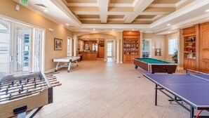 Ein geräumiger Innenbereich mit Kicker-, Billard- und Snookertischen. Es gibt eine Bar mit einer Theke und Flaschenregalen.
