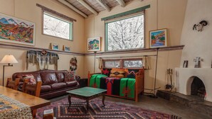 A cozy living room with a fireplace, leather sofa, and colorful rugs.