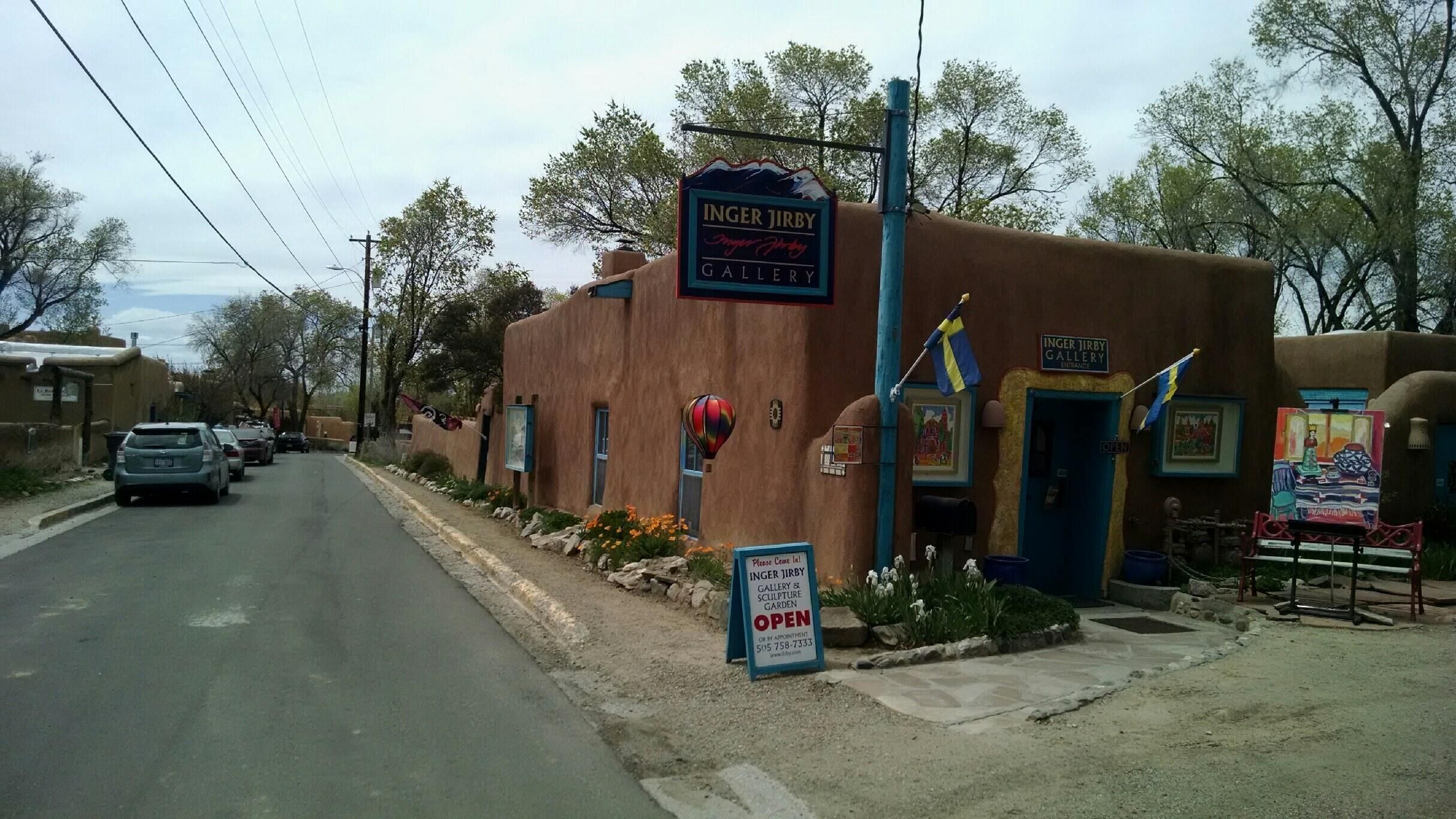 Un bâtiment sur lequel on peut lire l’inscription « GALERIE INGER JIRBY », ainsi qu’un autre panneau indiquant que la galerie et le jardin de sculptures sont ouverts.