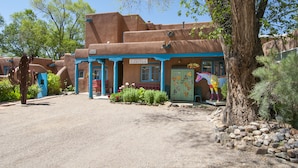 A building with a rustic exterior, a sign reading "CASITAS," and a tree in the foreground.
