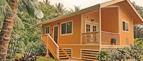 A wooden house with a balcony, a staircase, and a small porch area.