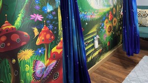 A room with a mural of a forest scene, a hanging chair, and a bed with a patterned pillow. - Climb On Inn-RRG- 3BD & 2BA - Outdoor Adventure Paradise- Pet Friendly -Cozy    (Pine Ridge)