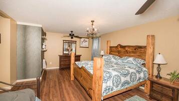 A bedroom with a wooden bed, a ceiling fan, a chandelier, and a nightstand with a lamp.