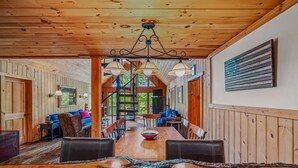 Un coin repas en bois avec une grande table, des chaises et un lustre.