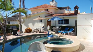 Un espace piscine comprenant un jacuzzi, des chaises longues et un barbecue.