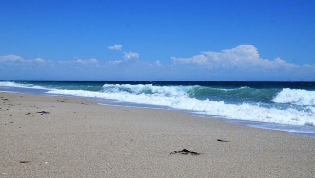 A beach with waves, clear sky, and a sandy shore.