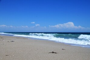 A beach with waves, clear sky, and a sandy shore.