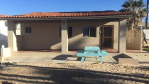 A single-story building with a tiled roof, a covered patio area, and a blue bench.
