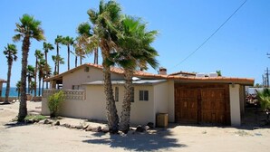 A single-story building with a tiled roof, a wooden door, and a small balcony.