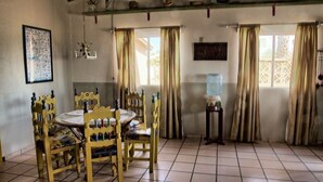 A dining area with a round table and chairs, a water dispenser, and curtains on the windows.