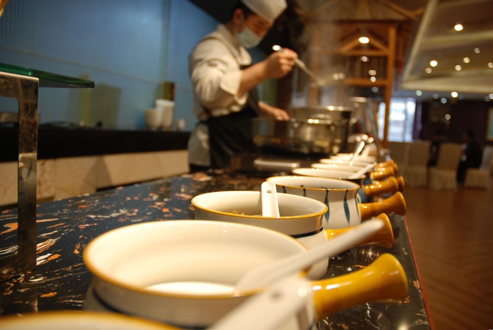 A row of white bowls with yellow handles on a counter.