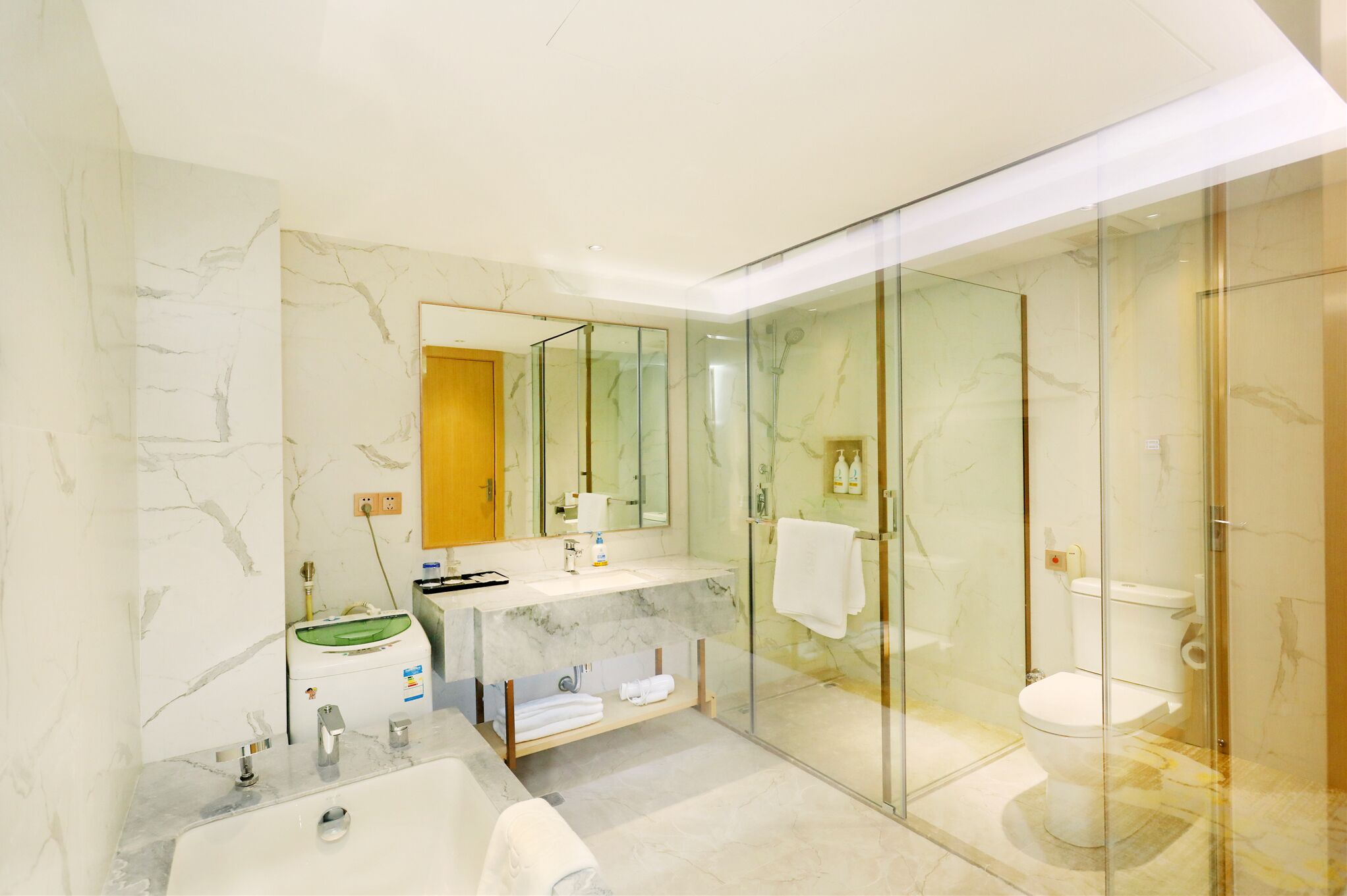 A modern bathroom with a marble vanity, a glass shower enclosure, and a toilet.