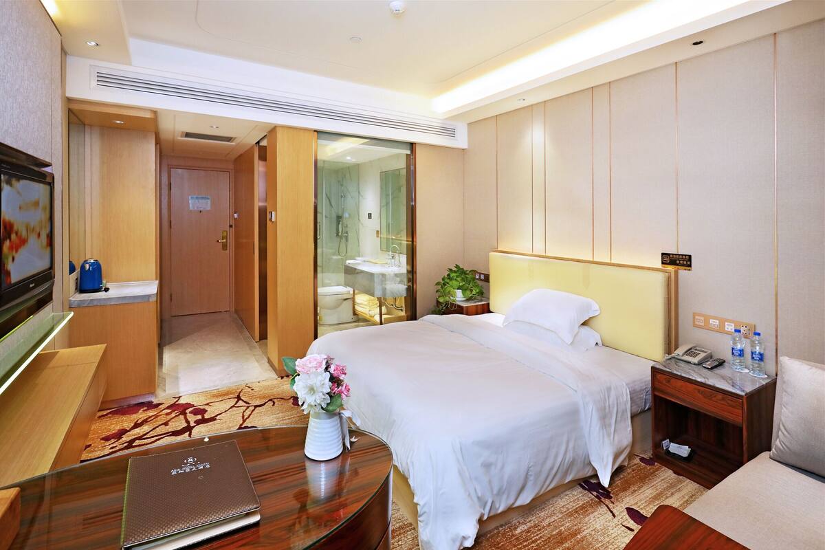 Una habitación de hotel con cama, mesita de noche, escritorio y televisión.