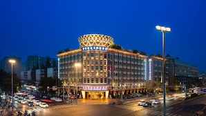 A multi-story hotel with a distinctive circular top and illuminated signage. - Gem Flower Jinyu Sunshine Hotel (Chengdu)