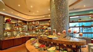 A buffet area with various food items, a central decorative column, and a counter with plates and bowls. - Gem Flower Jinyu Sunshine Hotel (Chengdu)