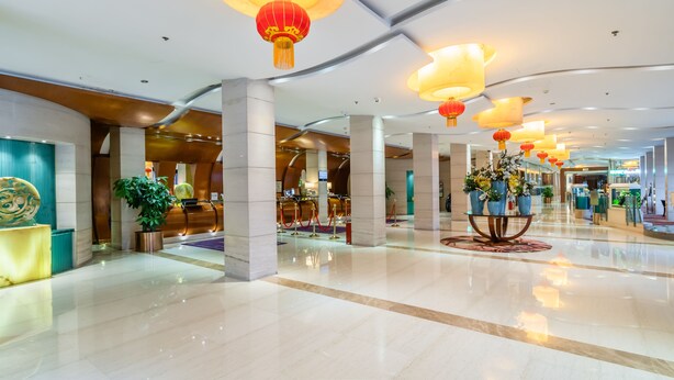 A spacious lobby with a polished marble floor, red lanterns, and a reception area with a plant and a decorative wall. - Gem Flower Jinyu Sunshine Hotel (Chengdu)