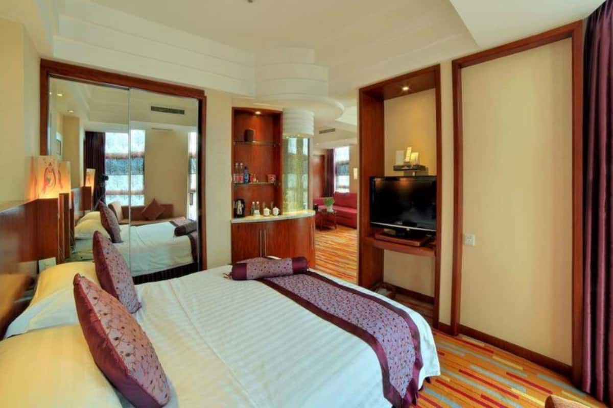 Ein Hotelzimmer mit einem großen Bett, einem Fernseher, einer Minibar und einem durch eine offene Tür einsehbaren Badezimmer.