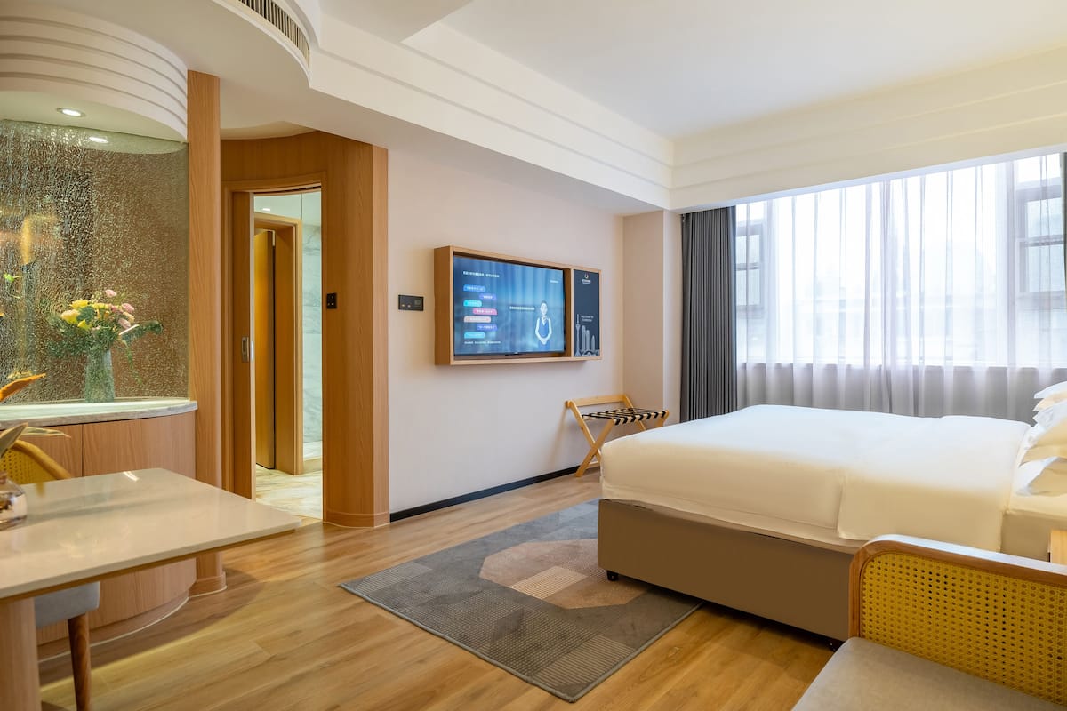 Ein Hotelzimmer mit einem großen Bett, einem Schreibtisch, einem Fernseher und Blick auf die Stadt durch das Fenster.