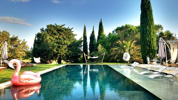 Una piscina con sillones de descanso y un flotador con forma de flamenco.