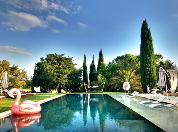 Een buitenzwembad, parasols bij het zwembad en ligstoelen