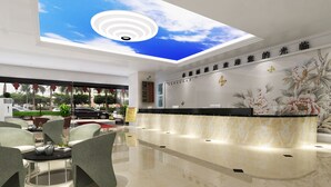 A hotel reception area with a modern design, featuring a reception desk, seating area with chairs, and a ceiling with a skylight.
