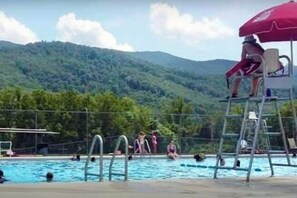 A swimming pool with a lifeguard chair and a red umbrella, surrounded by a forested hillside. - 7 Private Acres Minutes to Asheville NC/ Pet Friendly /5G Wi-Fi (Weaverville)