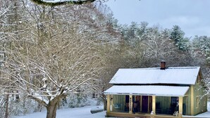 A wooden cabin with a snow-covered roof, surrounded by snow-laden trees.