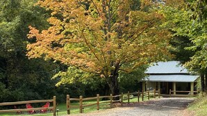 A gravel path leading to a wooden fence and a building with a metal roof.