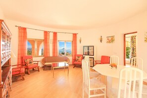 A cozy living room with a sofa, chairs, a dining table, and a bookshelf. - Villa Maryvilla - AFRODITA (Calp)
