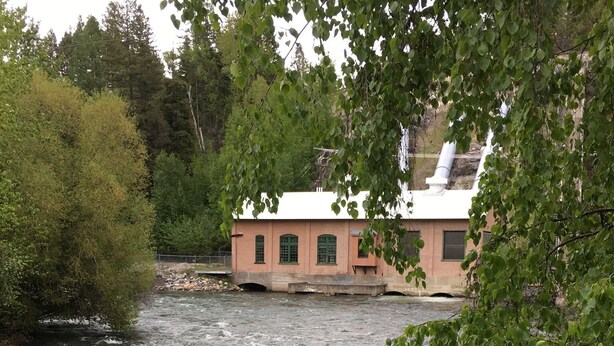 A river with a building in the background. - The Wild Mile River Retreat (Bigfork)