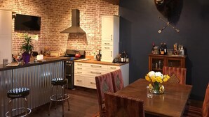 A kitchen with a brick wall, a mounted bull head, a bar area, and a dining table with chairs. - The Wild Mile River Retreat (Bigfork)