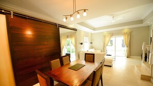 A spacious dining area with a wooden table and chairs, a sofa, and a staircase leading to an upper level.