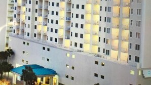 Ein mehrstöckiges Hotel mit symmetrischer Fassade, Balkonen in jeder Etage und einem überdachten Eingangsbereich.